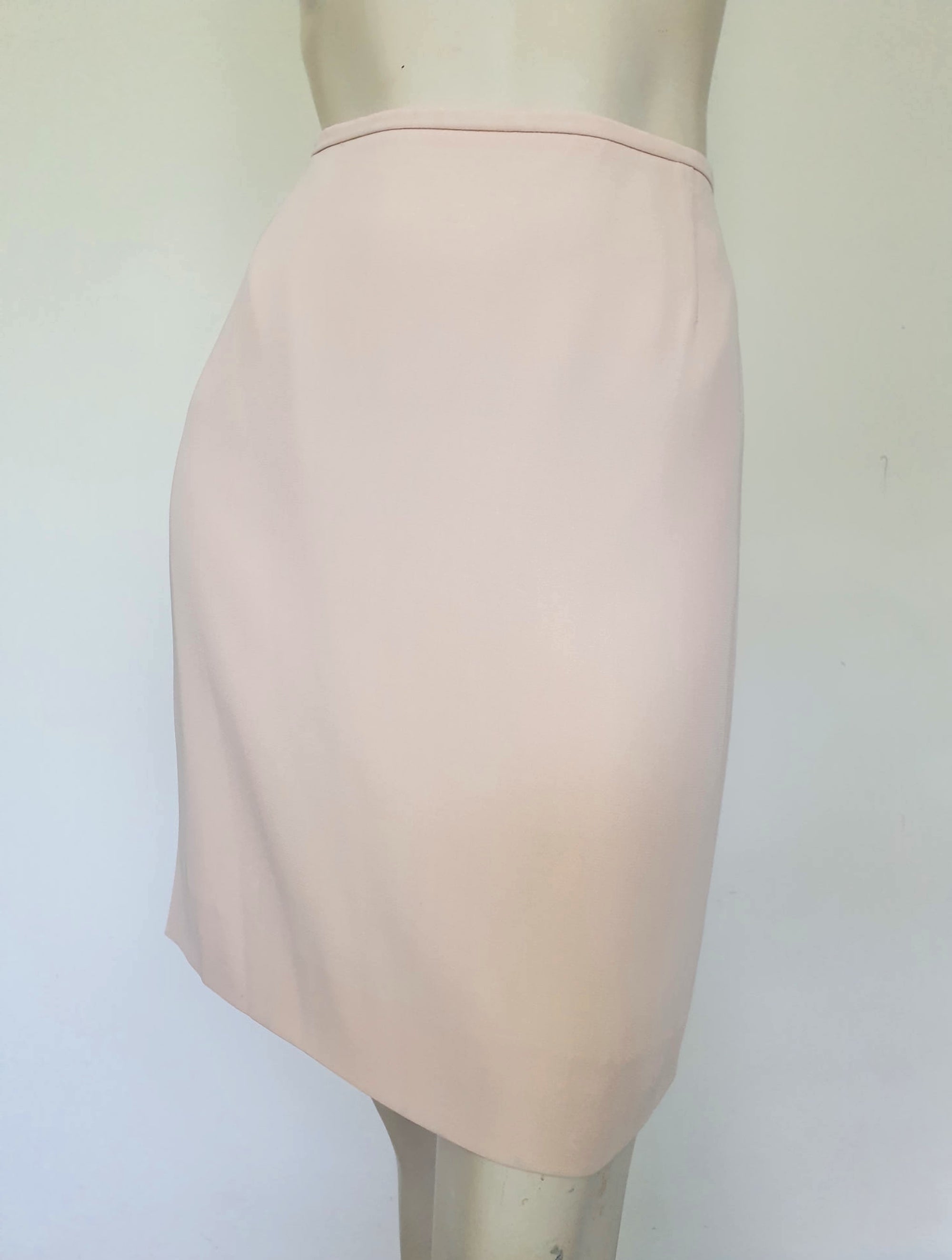 Above-knee length pale pink skirt and top set. Boxy top has short sleeves and is a pullover style, with a short opening buttoning at the back of the neck. There are removable shoulder pads. The straight skirt has a rear vent, rear zip and button fastening and is lined. Fabric is polyester crepe. Made in New Zealand for Suzanne Gregory - 1980s. Medium to Large.