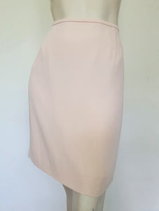 Above-knee length pale pink skirt and top set. Boxy top has short sleeves and is a pullover style, with a short opening buttoning at the back of the neck. There are removable shoulder pads. The straight skirt has a rear vent, rear zip and button fastening and is lined. Fabric is polyester crepe. Made in New Zealand for Suzanne Gregory - 1980s. Medium to Large.