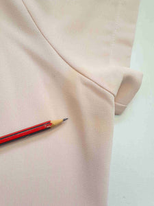 Above-knee length pale pink skirt and top set. Boxy top has short sleeves and is a pullover style, with a short opening buttoning at the back of the neck. There are removable shoulder pads. The straight skirt has a rear vent, rear zip and button fastening and is lined. Fabric is polyester crepe. Made in New Zealand for Suzanne Gregory - 1980s. Medium to Large.