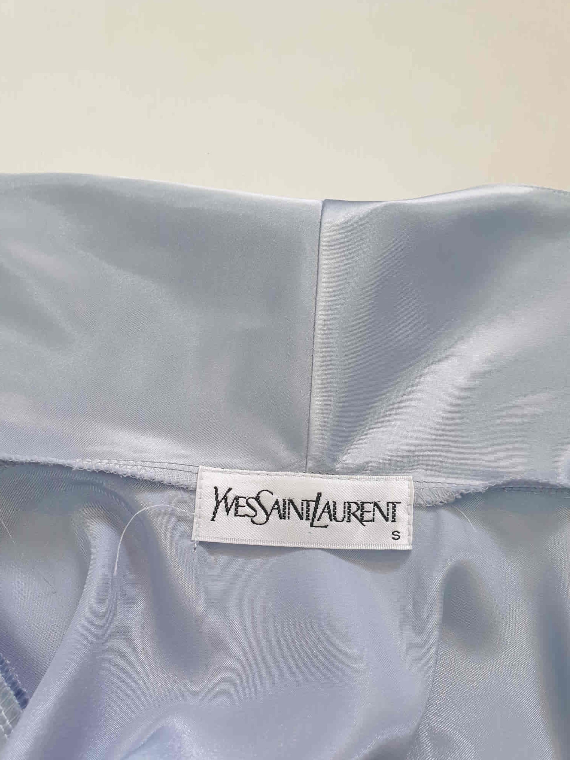 Beautiful blue satin robe with two patch pockets. Sleeves and pockets are trimmed with wide blue and white lace. Shawl collar and separate tie through carriers at the waist. Shoulder pads. Fabric is polyester satin. Made under licence in Australia for a famous French designer, see label - 1980s.