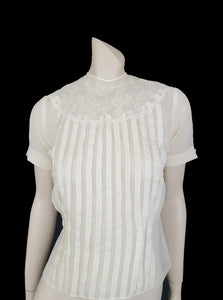 Beautiful little button back blouse - so pretty and feminine. Totally sheer nylon blouse has vertical tucks across the front and a circular yoke embellished with dainty applique work. The short sleeves have turn back cuffs. You will need to have someone to help you get dressed as it buttons down the back with shell buttons. It's darted in at the waist as it was designed to be tucked into a very high-waisted skirt. Brand is Park Lane, late 1950s-early 1960s. fits bust 92 cm/36".