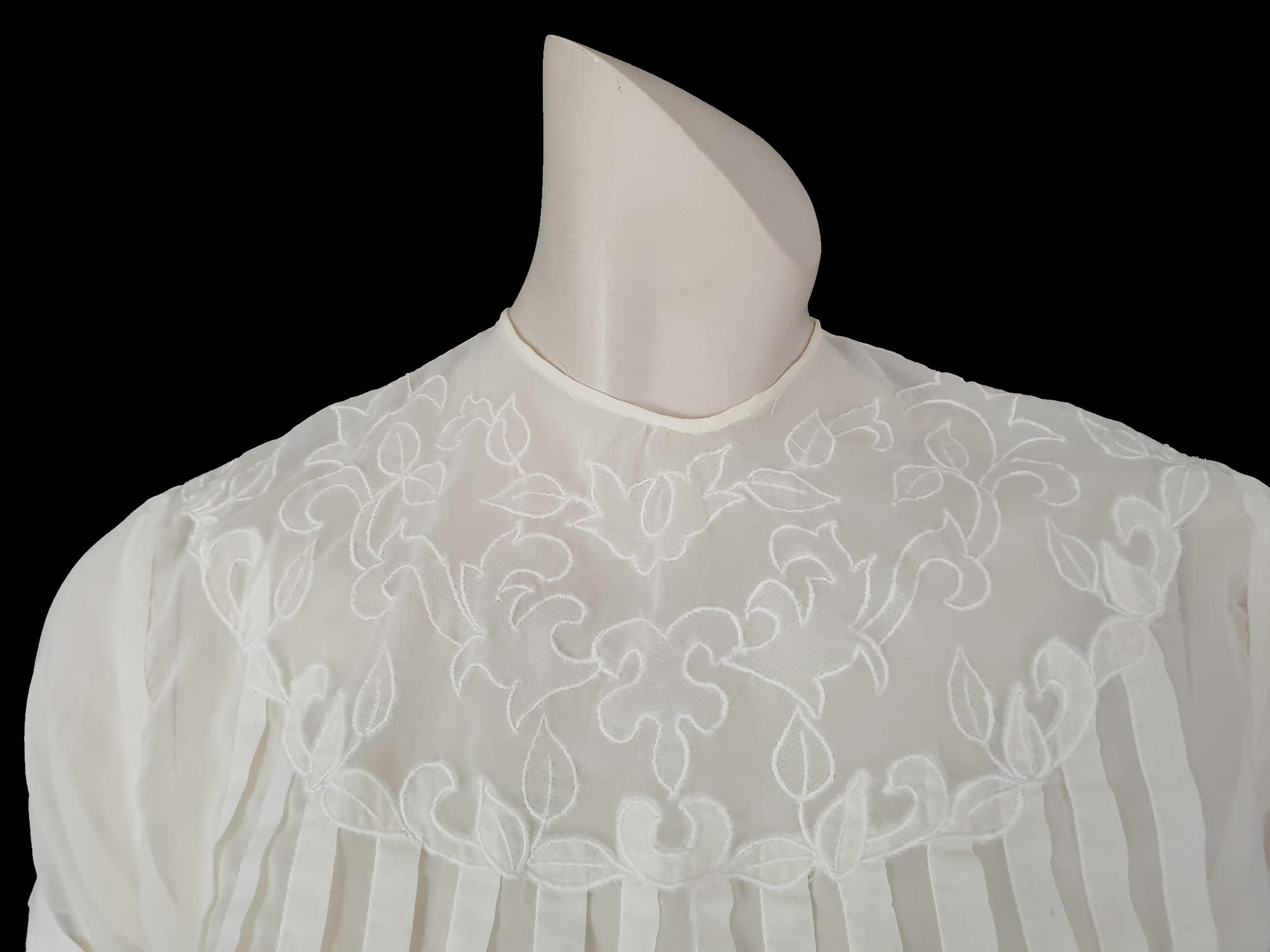 Beautiful little button back blouse - so pretty and feminine. Totally sheer nylon blouse has vertical tucks across the front and a circular yoke embellished with dainty applique work. The short sleeves have turn back cuffs. You will need to have someone to help you get dressed as it buttons down the back with shell buttons. It's darted in at the waist as it was designed to be tucked into a very high-waisted skirt. Brand is Park Lane, late 1950s-early 1960s. fits bust 92 cm/36".