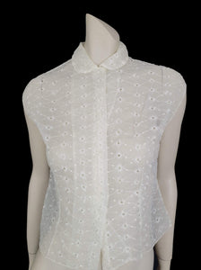 Beautiful sheer white nylon blouse embroidered all over in the eyelet style. 
The blouse has a peter pan collar and capped sleeves. It's darted in at the waist as it was designed to be worn with high waisted skirts. Closes to above waist level with clear plastic buttons. Fabric is nylon. No brand label. Late 1950s or very early 1960s. Medium
