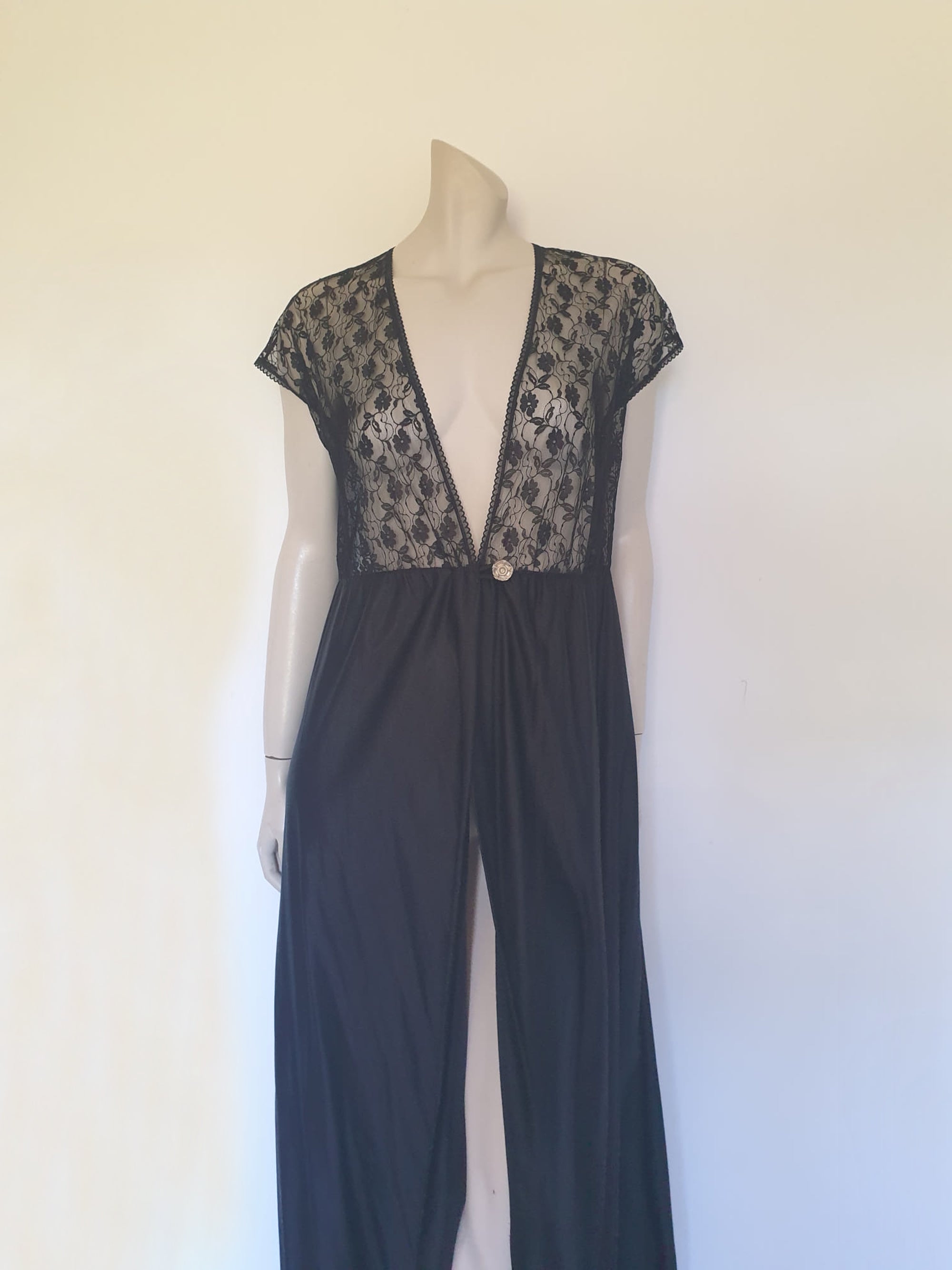 Black lace top robe style negligee is full length and has a dropped shoulder forming a cap sleeve effect. I have replaced the missing button at the waist with a silver vintage button. The waist is on elastic. Fabric is nylon. Made in South Africa for the party plan label "It's A Pleasure" - 1980s. Small.