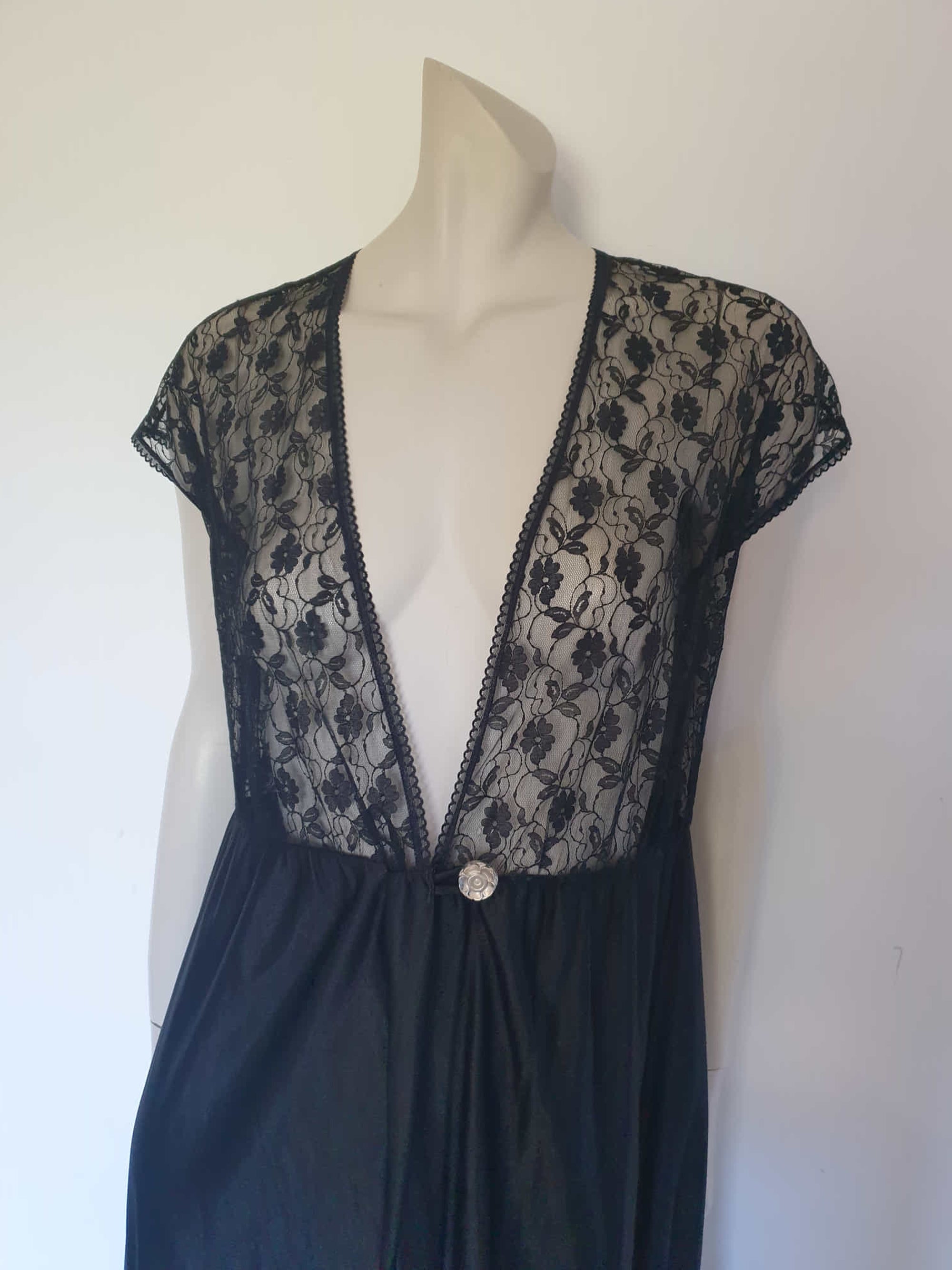 Black lace top robe style negligee is full length and has a dropped shoulder forming a cap sleeve effect. I have replaced the missing button at the waist with a silver vintage button. The waist is on elastic. Fabric is nylon. Made in South Africa for the party plan label "It's A Pleasure" - 1980s. Small.