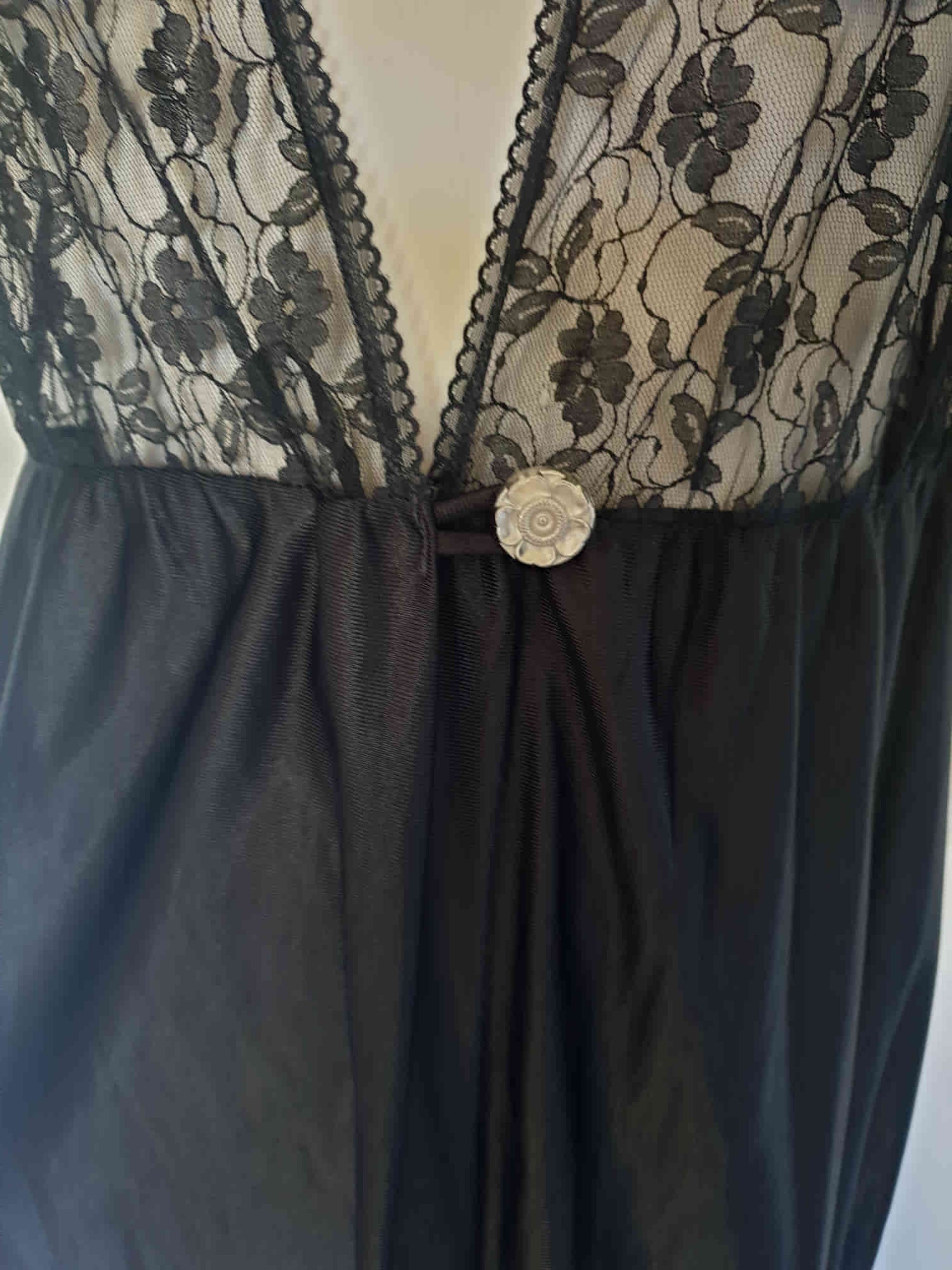 Black lace top robe style negligee is full length and has a dropped shoulder forming a cap sleeve effect. I have replaced the missing button at the waist with a silver vintage button. The waist is on elastic. Fabric is nylon. Made in South Africa for the party plan label "It's A Pleasure" - 1980s. Small.