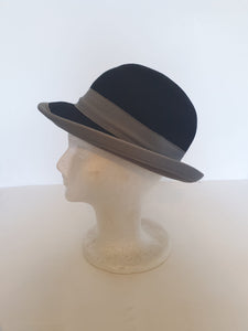 Felted bowler style black hat with grey grosgrain hatband and brim binding. Wear it bowler style with the brim up or turn the brim down for a bit of sass. Made in Denmark for Andersen &amp; Berner. 1980s??