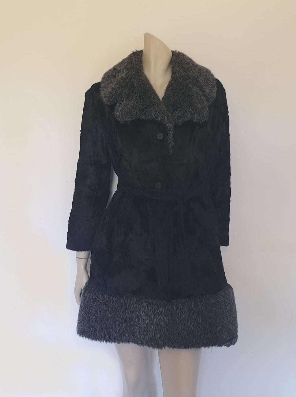 Fabulous little faux fur mini coat, just the thing that Twiggy might have worn. Black synthetic fur coat has a large fluffy grey collar and hem band. It has two side seam pockets and a matching tie running through carriers at the waist. Bound buttonholes. I have added three vintage metal buttons as the originals were missing. Fully lined with rayon or acetate. No labels at all - 1960s. Small.