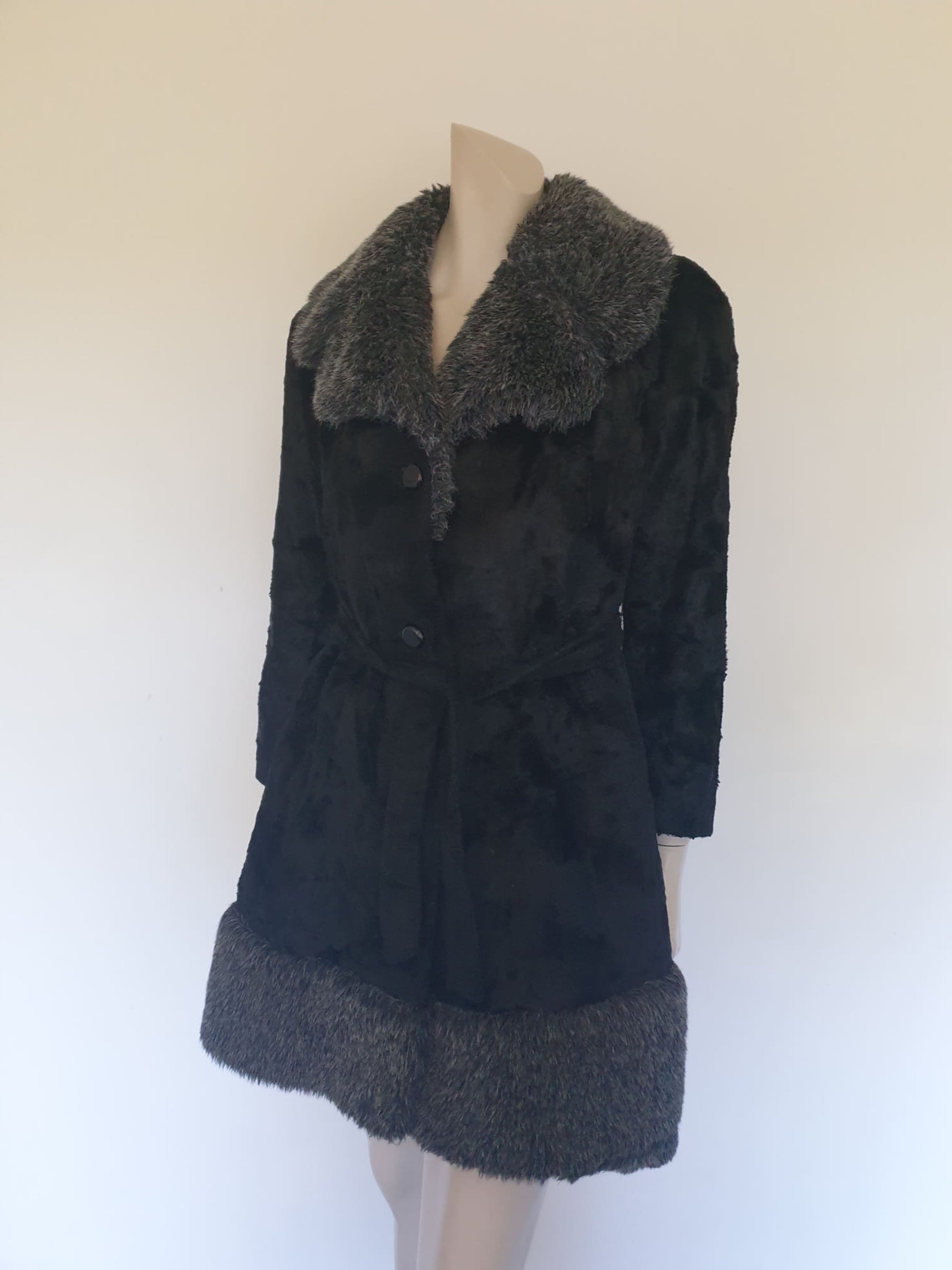 Fabulous little faux fur mini coat, just the thing that Twiggy might have worn. Black synthetic fur coat has a large fluffy grey collar and hem band. It has two side seam pockets and a matching tie running through carriers at the waist. Bound buttonholes. I have added three vintage metal buttons as the originals were missing. Fully lined with rayon or acetate. No labels at all - 1960s. Small.