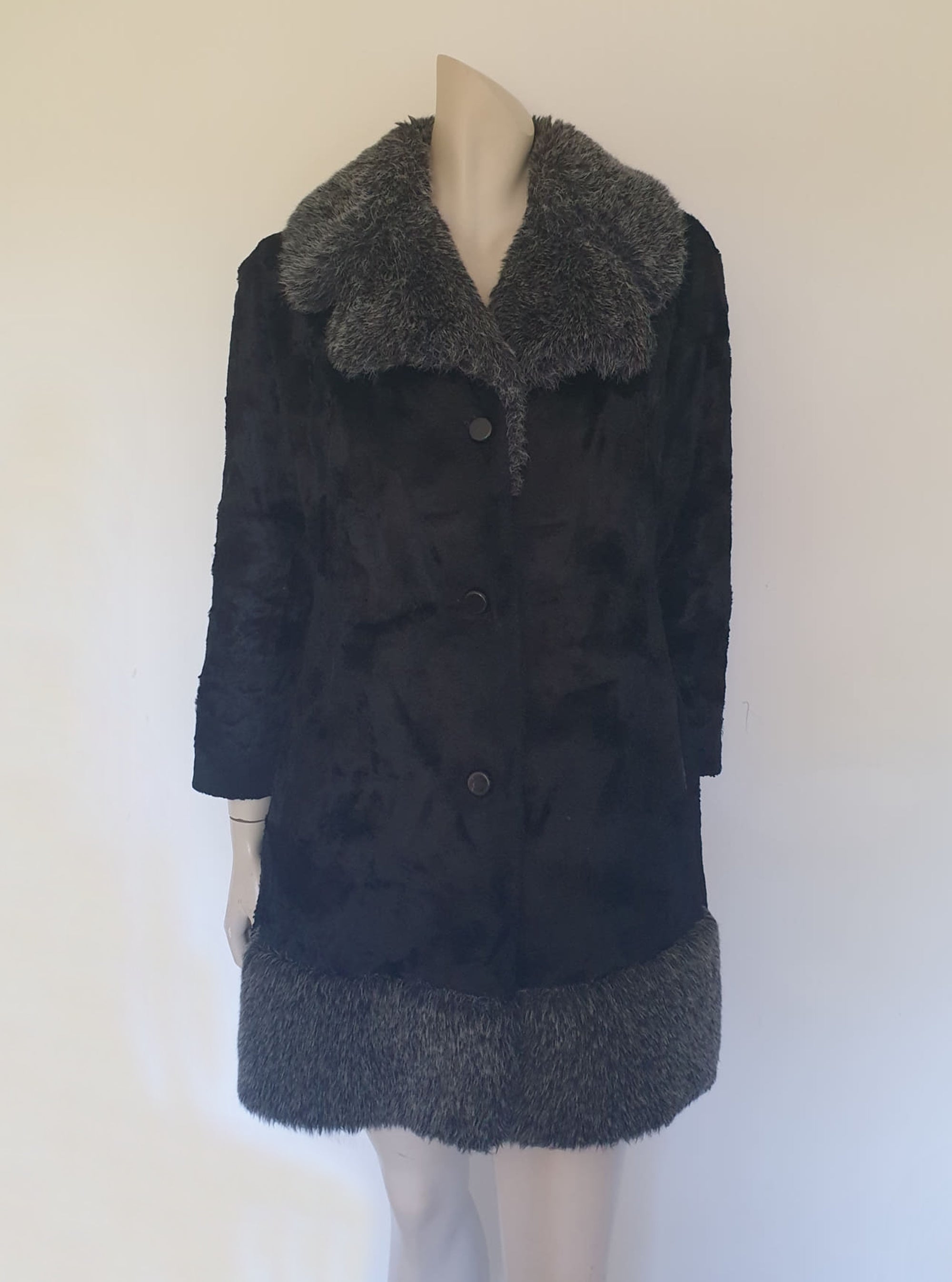 Fabulous little faux fur mini coat, just the thing that Twiggy might have worn. Black synthetic fur coat has a large fluffy grey collar and hem band. It has two side seam pockets and a matching tie running through carriers at the waist. Bound buttonholes. I have added three vintage metal buttons as the originals were missing. Fully lined with rayon or acetate. No labels at all - 1960s. Small.