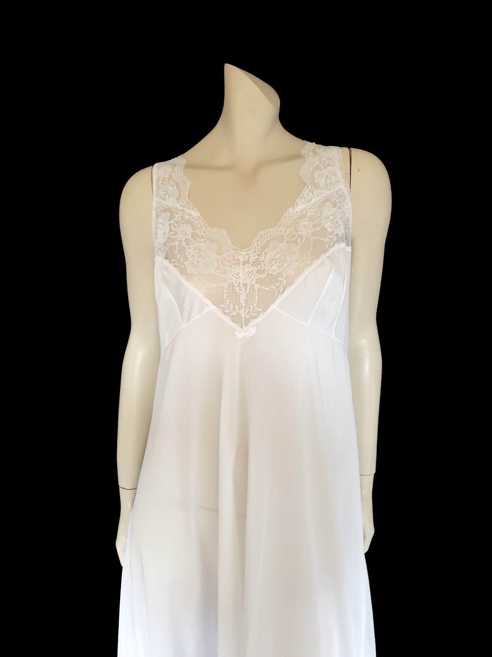 Below-knee to mid-calf length white midi slip has lace over the bust extending into wide front straps. Deep lace border also has ribbon trim. The straps are not adjustable. Fabric is nylon. Made in Australia. There is no brand label. 1980s-1990s. Medium