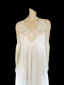 Below-knee to mid-calf length white midi slip has lace over the bust extending into wide front straps. Deep lace border also has ribbon trim. The straps are not adjustable. Fabric is nylon. Made in Australia. There is no brand label. 1980s-1990s. Medium