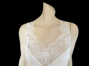Below-knee to mid-calf length white midi slip has lace over the bust extending into wide front straps. Deep lace border also has ribbon trim. The straps are not adjustable. Fabric is nylon. Made in Australia. There is no brand label. 1980s-1990s. Medium