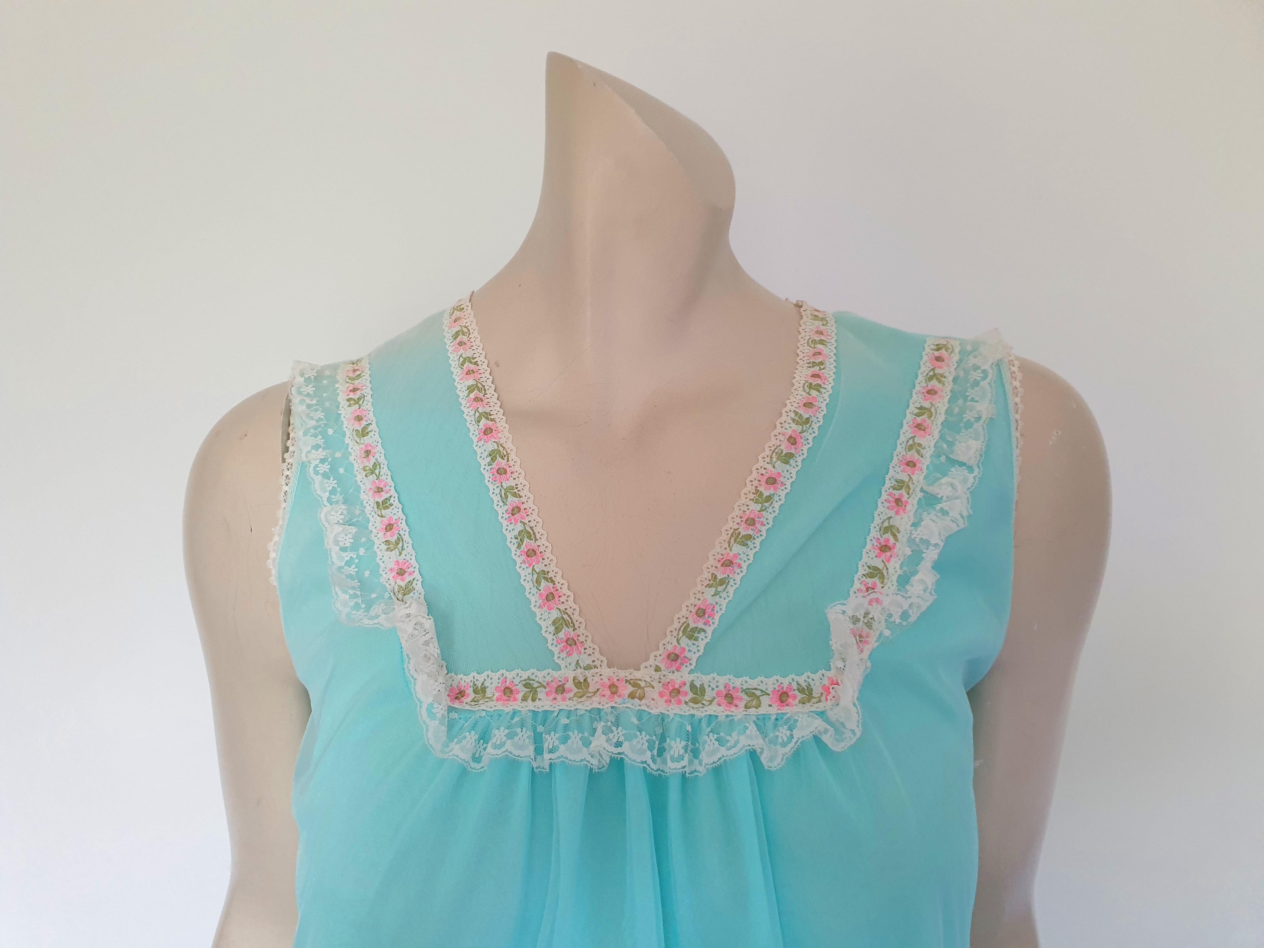 Very cute little aqua mini nightgown with floral braid and lace trim at the V neckline. The same lace also trims the hem. The nightie has a sheer overlay with an opaque layer of fabric beneath. Fabric is nylon. Brand is Irene Lingerie - Late 1960s - 1970s. Small.