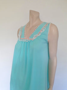 Very cute little aqua mini nightgown with floral braid and lace trim at the V neckline. The same lace also trims the hem. The nightie has a sheer overlay with an opaque layer of fabric beneath. Fabric is nylon. Brand is Irene Lingerie - Late 1960s - 1970s. Small.