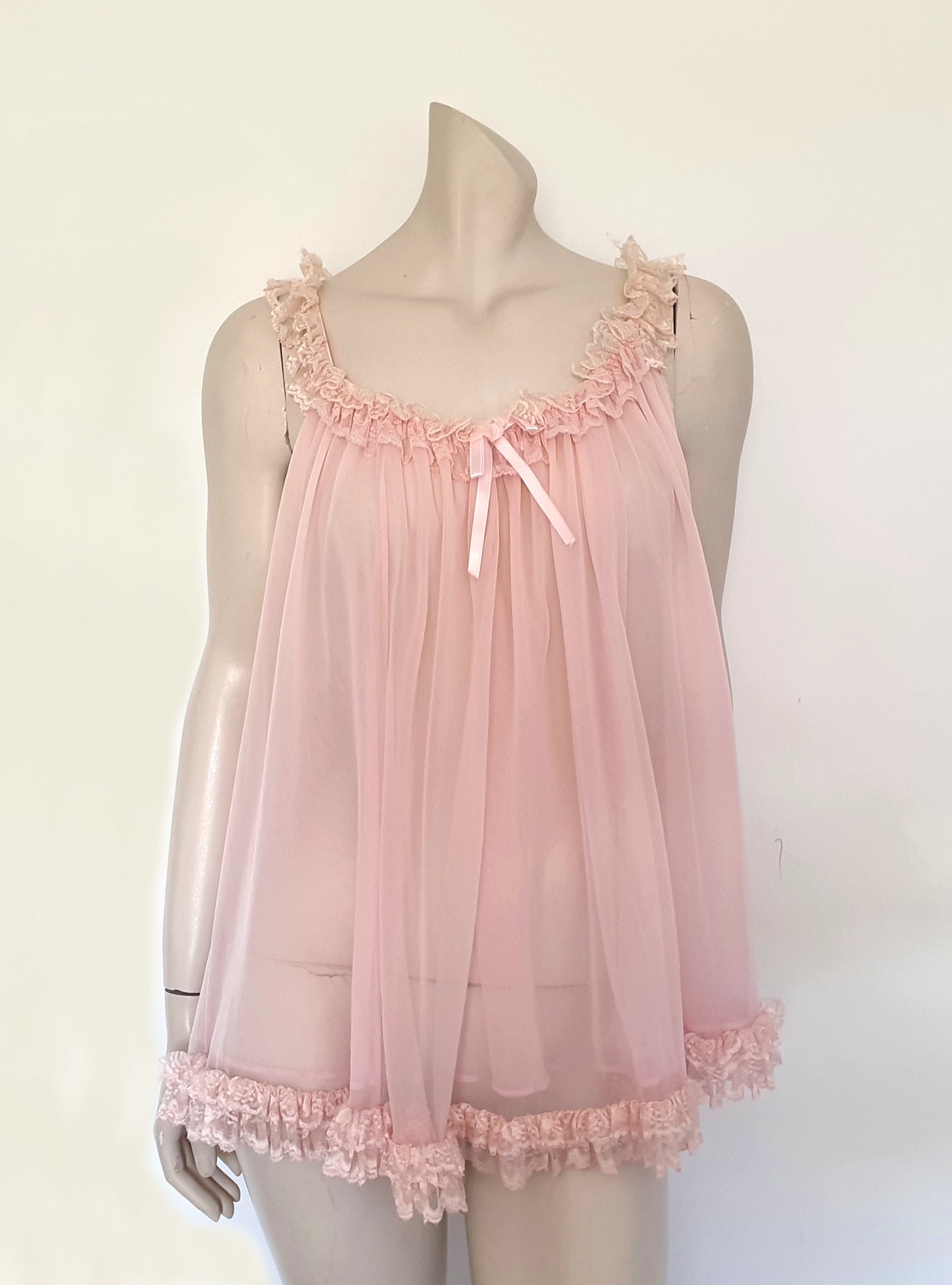 Pink Babydoll has a wide scooped neckline extending into straps. The neckline and the straps are  on elastic and are trimmed with wide ruffled lace. The same lace trims the hem. Ribbon bow at the front. The underarms are also elasticised. It's made from two layers of sheer nylon. Label reads S.G. for Escante, and appears to be a reproduction of the popular '60 style made likely in the 1990s. Extra large, marked 3XL