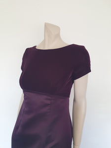 Beautiful and elegant aubergine formal sheath style gown with velvet bodice and stunning rear view. The gown has a wide neckline cut low at the back where it features a diamante studded bow extending into a narrow train over the the rear of the dress. Beneath the train the gown is slit to above the knee. The bodice is velvet and the satin skirt falls from beneath the bust. Closes at the back with a zip and a fancy button. Fabric is polyester. Made in Australia. Brand is Aurelie - 1980s. XS