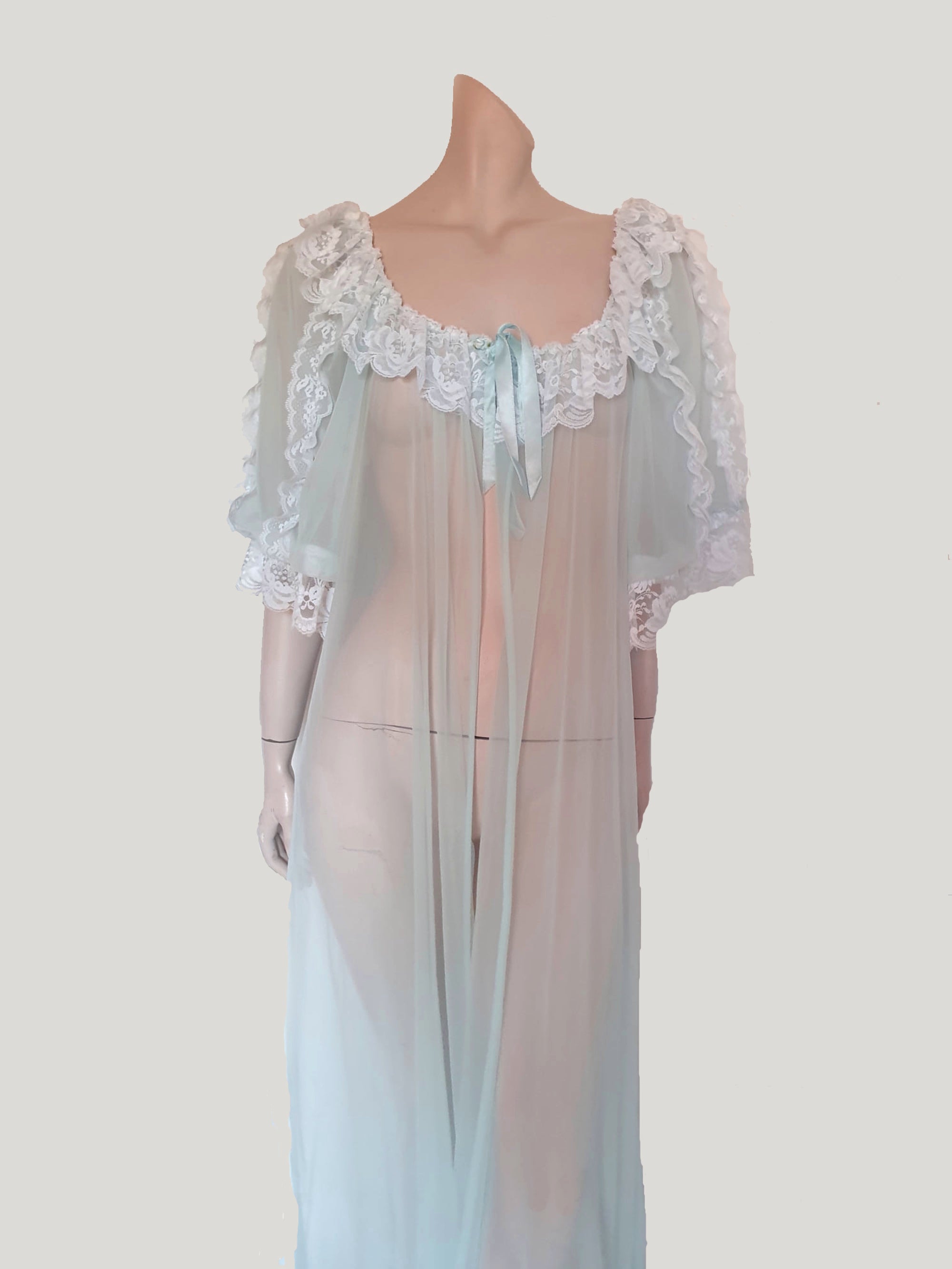 Sheer and sexy vintage glamour. This beautiful peignoir or robe is pale aqua or blue depending on the light, and is trimmed with white white lace. Low, scooped neckline at the front and back. The wide, full sleeves come to below the elbow . Open at the front and ties at the breast with a ribbon. Fabric is nylon. The labels have been removed. 1960s. Medium