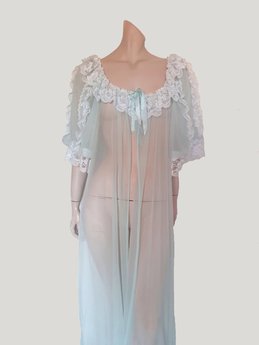Sheer and sexy vintage glamour. This beautiful peignoir or robe is pale aqua or blue depending on the light, and is trimmed with white white lace. Low, scooped neckline at the front and back. The wide, full sleeves come to below the elbow . Open at the front and ties at the breast with a ribbon. Fabric is nylon. The labels have been removed. 1960s. Medium