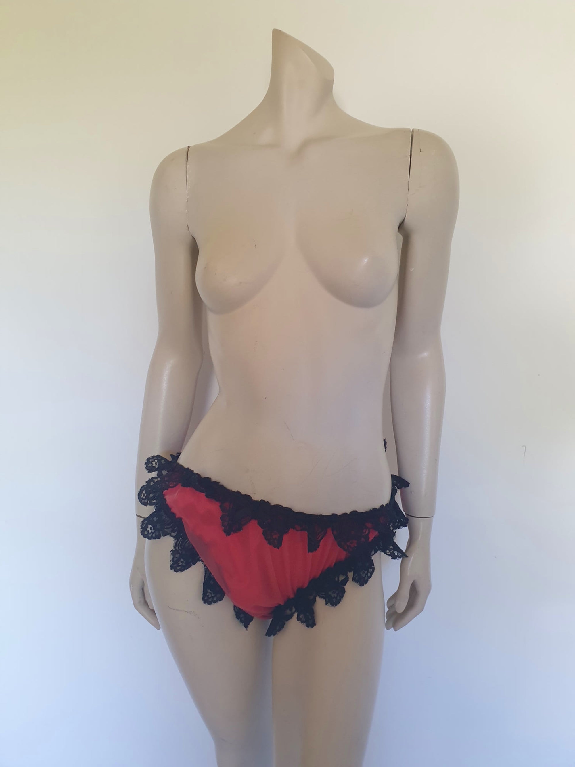 Red bikini style sleepwear panties, most likely worn with a babydoll, sheer gown or PJ top. These have a sheer nylon overlay and are trimmed with wide, scalloped black lace and a ribbon bow. No cotton gusset. Fabric is nylon. There are no tags. Medium