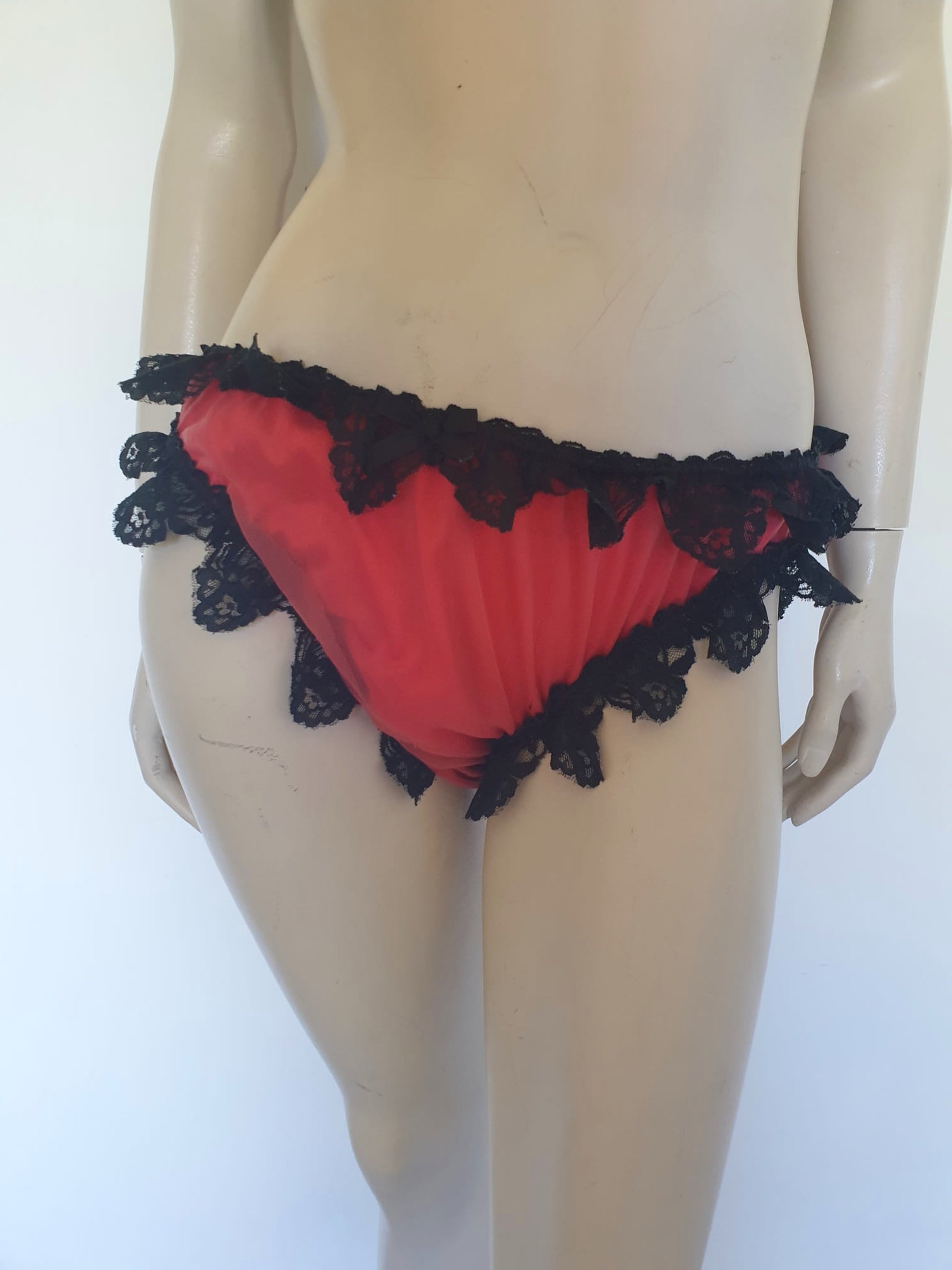 Red bikini style sleepwear panties, most likely worn with a babydoll, sheer gown or PJ top. These have a sheer nylon overlay and are trimmed with wide, scalloped black lace and a ribbon bow. No cotton gusset. Fabric is nylon. There are no tags. Medium