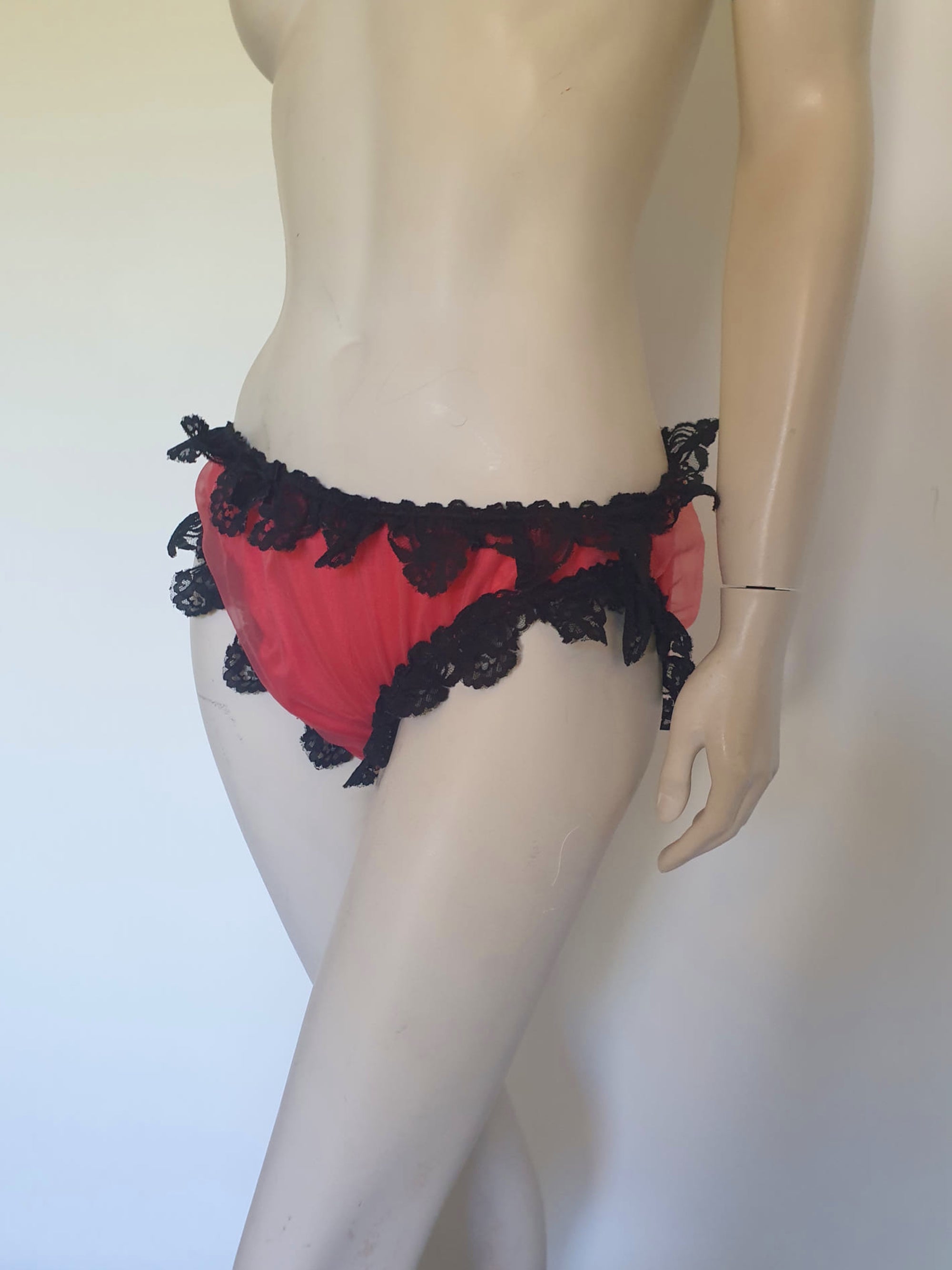Red bikini style sleepwear panties, most likely worn with a babydoll, sheer gown or PJ top. These have a sheer nylon overlay and are trimmed with wide, scalloped black lace and a ribbon bow. No cotton gusset. Fabric is nylon. There are no tags. Medium