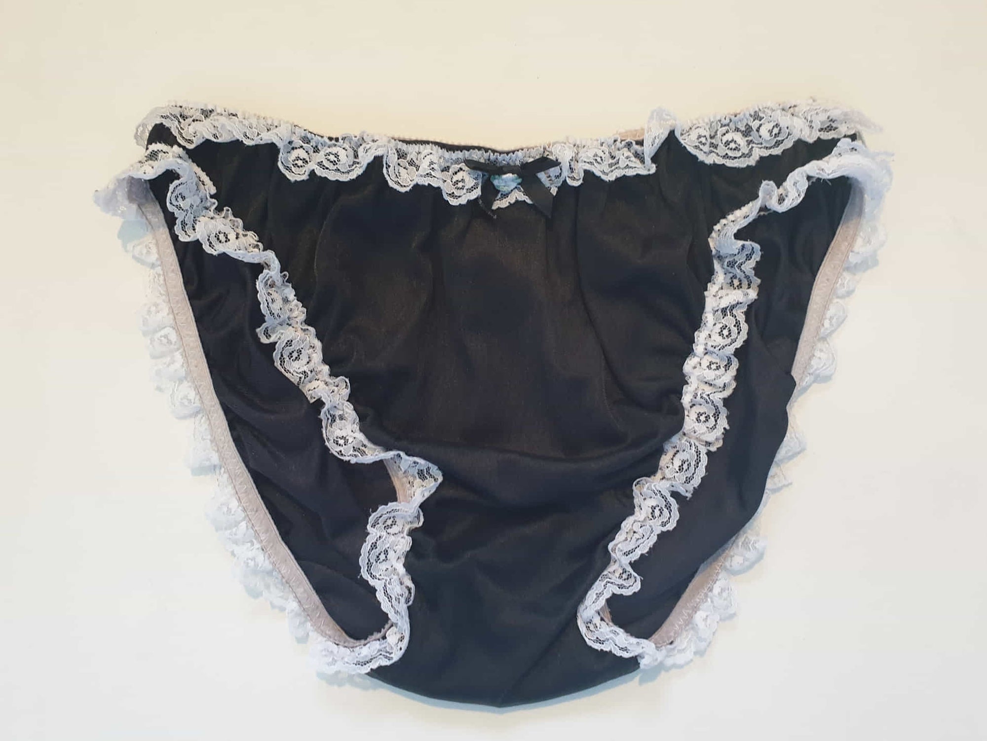 Black sleepwear panties with white lace - the kind you would wear with a babydoll or other sleep top or short nightgown. Panties are high cut and trimmed at the top and leg edges with wide white lace. A little bow finishes off the front. They are made of two layers of nylon, the inner layer is opaque and the outer layer is sheer. There is no cotton gusset and no labels. 1980s-1990s. Medium