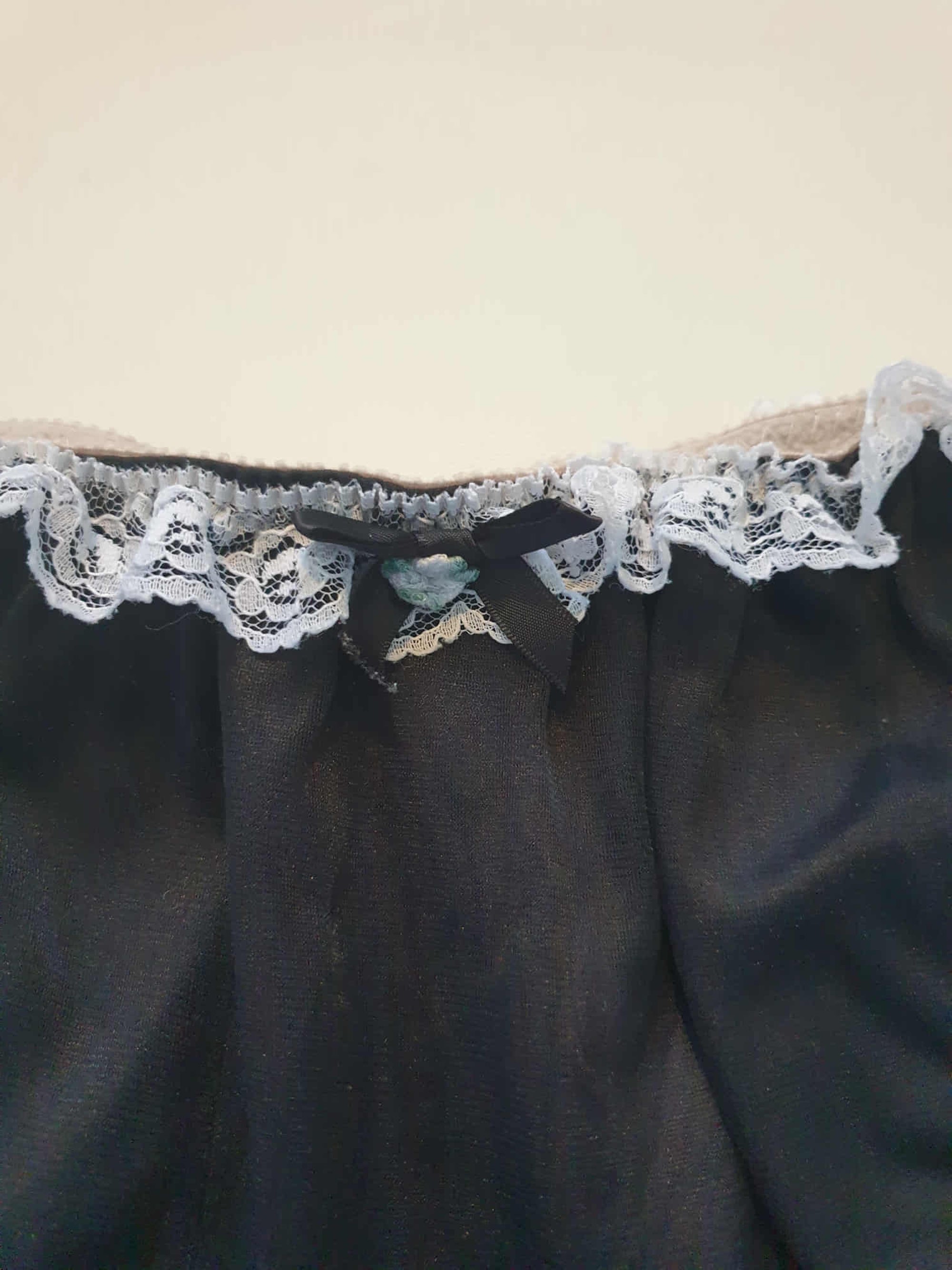 Black sleepwear panties with white lace - the kind you would wear with a babydoll or other sleep top or short nightgown. Panties are high cut and trimmed at the top and leg edges with wide white lace. A little bow finishes off the front. They are made of two layers of nylon, the inner layer is opaque and the outer layer is sheer. There is no cotton gusset and no labels. 1980s-1990s. Medium