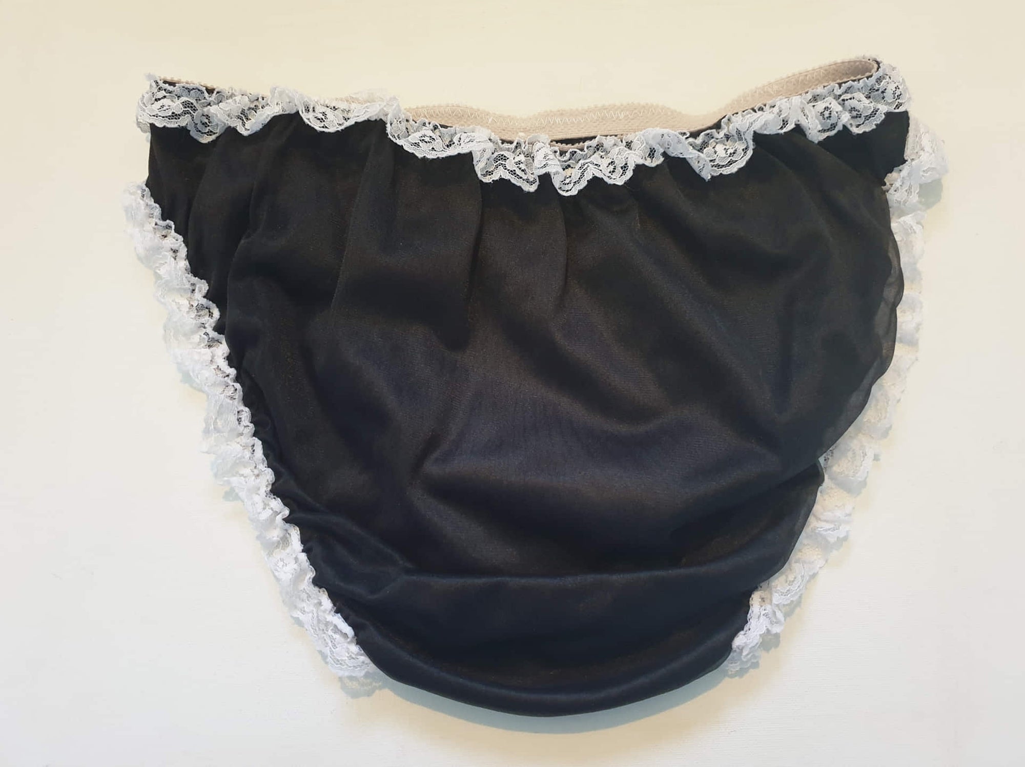 Black sleepwear panties with white lace - the kind you would wear with a babydoll or other sleep top or short nightgown. Panties are high cut and trimmed at the top and leg edges with wide white lace. A little bow finishes off the front. They are made of two layers of nylon, the inner layer is opaque and the outer layer is sheer. There is no cotton gusset and no labels. 1980s-1990s. Medium