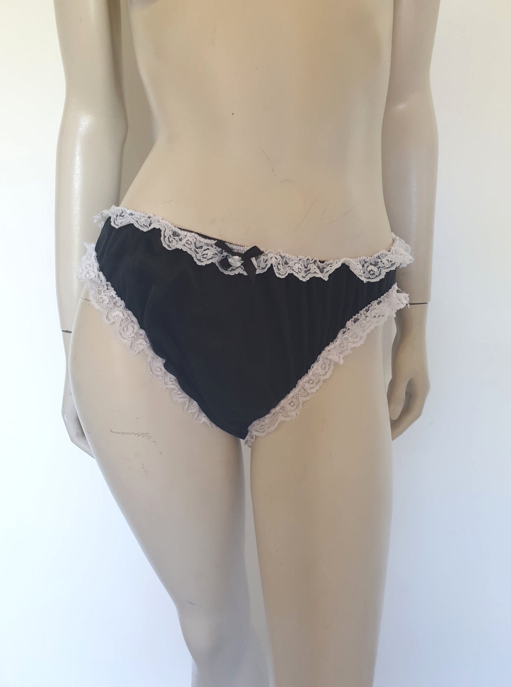 Black sleepwear panties with white lace - the kind you would wear with a babydoll or other sleep top or short nightgown. Panties are high cut and trimmed at the top and leg edges with wide white lace. A little bow finishes off the front. They are made of two layers of nylon, the inner layer is opaque and the outer layer is sheer. There is no cotton gusset and no labels. 1980s-1990s. Medium