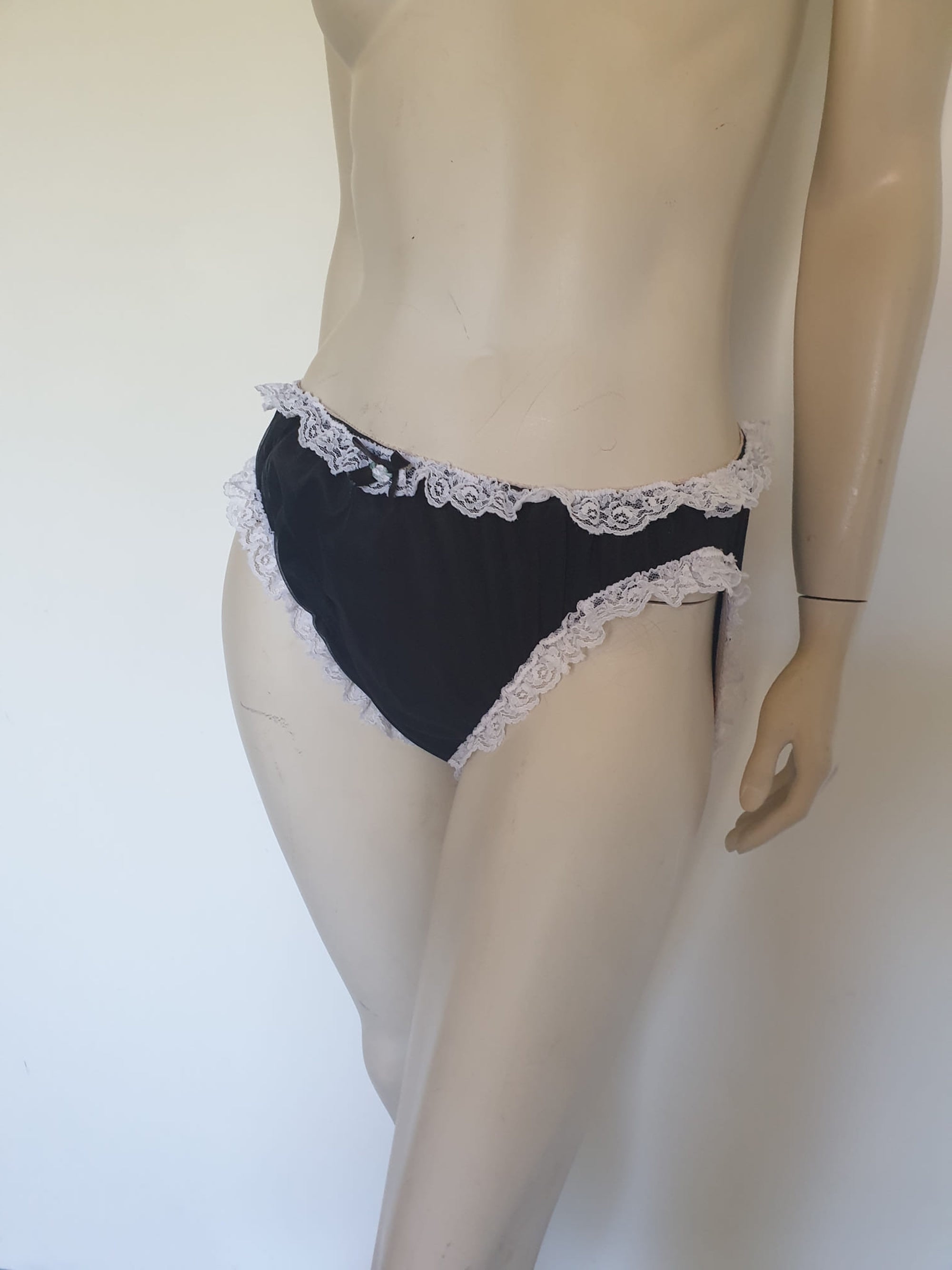 Black sleepwear panties with white lace - the kind you would wear with a babydoll or other sleep top or short nightgown. Panties are high cut and trimmed at the top and leg edges with wide white lace. A little bow finishes off the front. They are made of two layers of nylon, the inner layer is opaque and the outer layer is sheer. There is no cotton gusset and no labels. 1980s-1990s. Medium