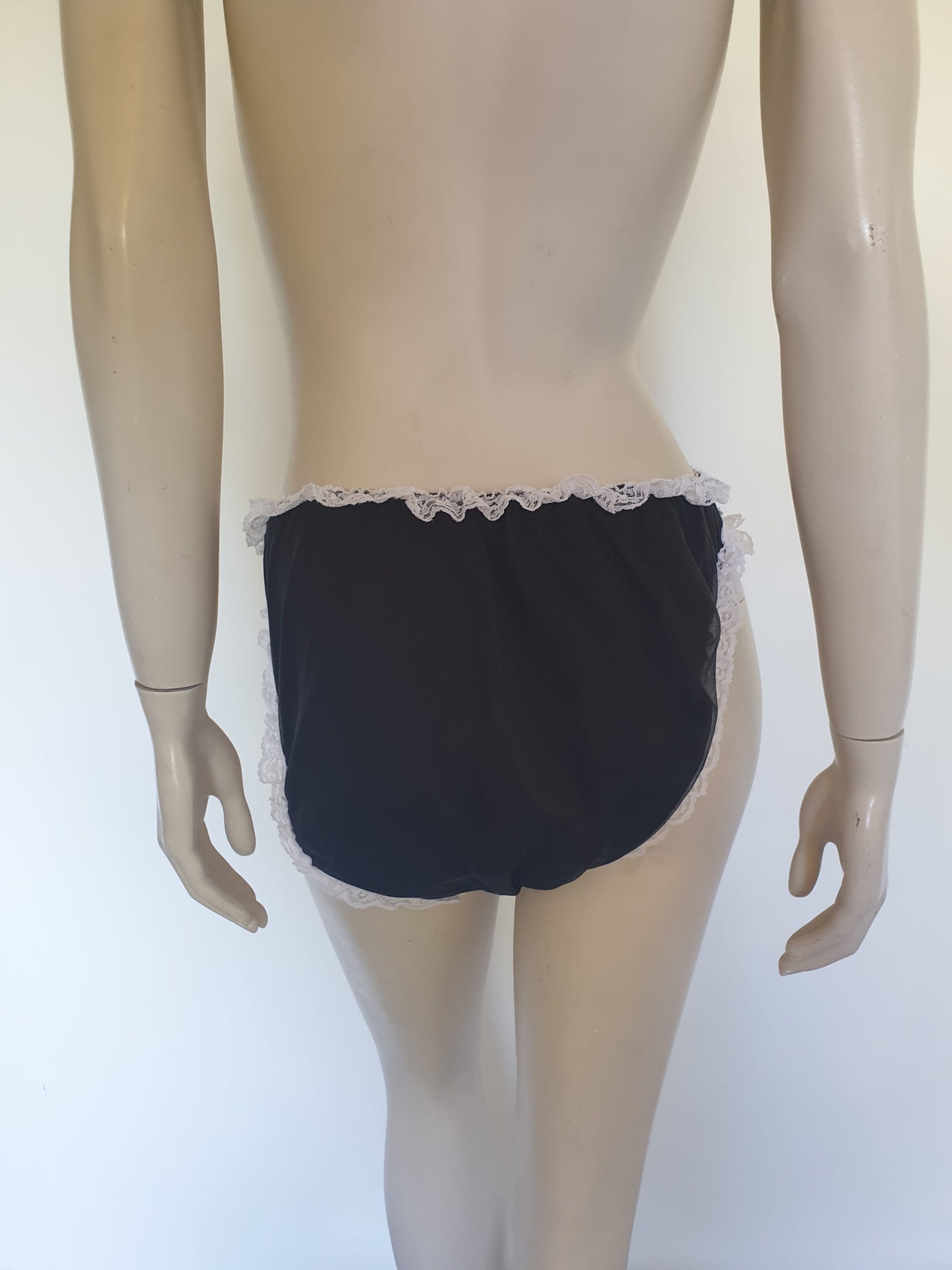 Black sleepwear panties with white lace - the kind you would wear with a babydoll or other sleep top or short nightgown. Panties are high cut and trimmed at the top and leg edges with wide white lace. A little bow finishes off the front. They are made of two layers of nylon, the inner layer is opaque and the outer layer is sheer. There is no cotton gusset and no labels. 1980s-1990s. Medium