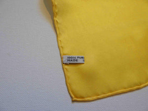 Yellow silk pocket square has hand rolled edges. Tag says 100% pure silk - Made in China.