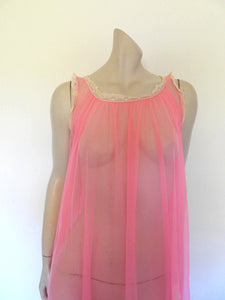 Super sexy sheer hot pink negligee nightgown. Has some issues but presents well. Very full negligee has wide neckline trimmed with cream lace. The hem is trimmed with a deep border of cream lace. There's a fixed tie at centre back which can tie in the fullness if you prefer. I have appliqued two flowers over two large holes in the front. Fabric is a single layer of sheer nylon. Made in the USA for Berkliff - 1960s. Small to Medium.