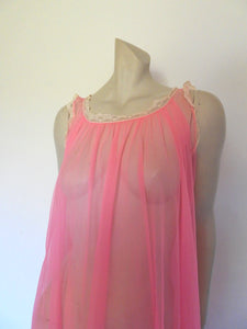 Super sexy sheer hot pink negligee nightgown. Has some issues but presents well. Very full negligee has wide neckline trimmed with cream lace. The hem is trimmed with a deep border of cream lace. There's a fixed tie at centre back which can tie in the fullness if you prefer. I have appliqued two flowers over two large holes in the front. Fabric is a single layer of sheer nylon. Made in the USA for Berkliff - 1960s. Small to Medium.