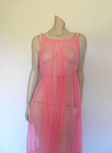 Super sexy sheer hot pink negligee nightgown. Has some issues but presents well. Very full negligee has wide neckline trimmed with cream lace. The hem is trimmed with a deep border of cream lace. There's a fixed tie at centre back which can tie in the fullness if you prefer. I have appliqued two flowers over two large holes in the front. Fabric is a single layer of sheer nylon. Made in the USA for Berkliff - 1960s. Small to Medium.