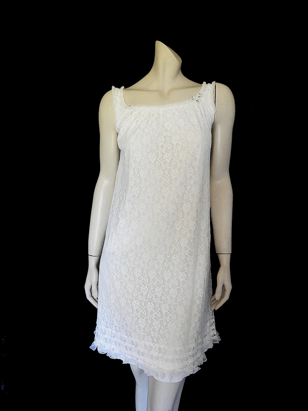 Pretty white lace knee-length nightgown would also make a sweet dress.
The nightie has scooped neckline front and back, horizontal tucks at the hem and ruffle trim at the neckline, armholes and hem. The neckline is trimmed with flower appliques. There is an opaque layer beneath the lace outer layer and this hangs down a little below the lace at the bottom. Nylon lace with acetate lining. Brand is St Mark, 1960s. Small.