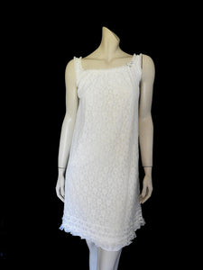 Pretty white lace knee-length nightgown would also make a sweet dress.
The nightie has scooped neckline front and back, horizontal tucks at the hem and ruffle trim at the neckline, armholes and hem. The neckline is trimmed with flower appliques. There is an opaque layer beneath the lace outer layer and this hangs down a little below the lace at the bottom. Nylon lace with acetate lining. Brand is St Mark, 1960s. Small.