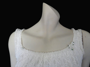 Pretty white lace knee-length nightgown would also make a sweet dress.
The nightie has scooped neckline front and back, horizontal tucks at the hem and ruffle trim at the neckline, armholes and hem. The neckline is trimmed with flower appliques. There is an opaque layer beneath the lace outer layer and this hangs down a little below the lace at the bottom. Nylon lace with acetate lining. Brand is St Mark, 1960s. Small.