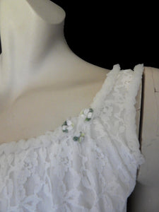 Pretty white lace knee-length nightgown would also make a sweet dress.
The nightie has scooped neckline front and back, horizontal tucks at the hem and ruffle trim at the neckline, armholes and hem. The neckline is trimmed with flower appliques. There is an opaque layer beneath the lace outer layer and this hangs down a little below the lace at the bottom. Nylon lace with acetate lining. Brand is St Mark, 1960s. Small.