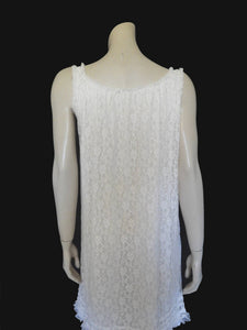 Pretty white lace knee-length nightgown would also make a sweet dress.
The nightie has scooped neckline front and back, horizontal tucks at the hem and ruffle trim at the neckline, armholes and hem. The neckline is trimmed with flower appliques. There is an opaque layer beneath the lace outer layer and this hangs down a little below the lace at the bottom. Nylon lace with acetate lining. Brand is St Mark, 1960s. Small.