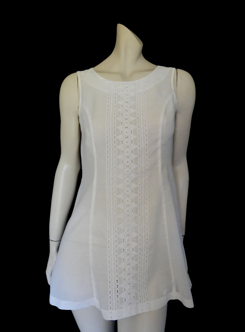 Tennis dress is decorated at centre front with eyelet embroidery. It has princess seaming and closes at the back with a zipper. The dress is semi sheer. The fabric appears to be an early form of polyester or maybe nylon, there's no fabric tag. The label reads "A Belle Garment Exclusive Model" - early 1960s. Medium