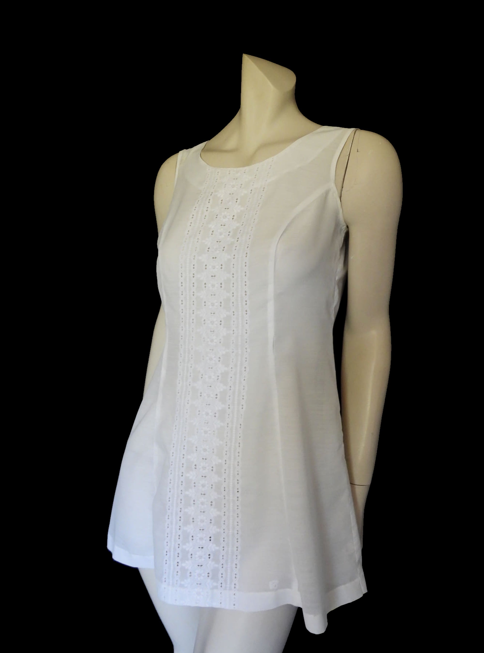 Tennis dress is decorated at centre front with eyelet embroidery. It has princess seaming and closes at the back with a zipper. The dress is semi sheer. The fabric appears to be an early form of polyester or maybe nylon, there's no fabric tag. The label reads "A Belle Garment Exclusive Model" - early 1960s. Medium