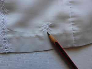 Tennis dress is decorated at centre front with eyelet embroidery. It has princess seaming and closes at the back with a zipper. The dress is semi sheer. The fabric appears to be an early form of polyester or maybe nylon, there's no fabric tag. The label reads "A Belle Garment Exclusive Model" - early 1960s. Medium