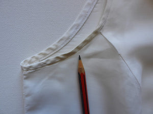 Tennis dress is decorated at centre front with eyelet embroidery. It has princess seaming and closes at the back with a zipper. The dress is semi sheer. The fabric appears to be an early form of polyester or maybe nylon, there's no fabric tag. The label reads "A Belle Garment Exclusive Model" - early 1960s. Medium