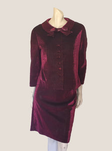 Very cute purple lurex skirt suit. Has some issues including alteration of the skirt. The jacket has a wide collar and neck bow trim. Sleeves are bracelet length. Straight, above-knee length skirt closes with a metal zipper in one side. The jacket is lined. The fabric is Lurex. The skirt stretches but the lining prevents the jacket from stretching. Made by Vera Fashions Sydney - 1960s.  Medium